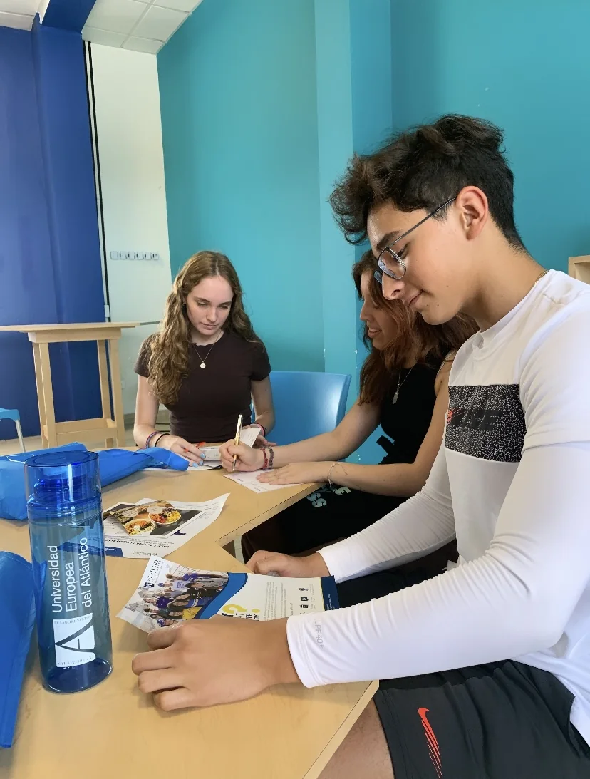 Estudiantes de preparatoria colaborando alrededor de una mesa